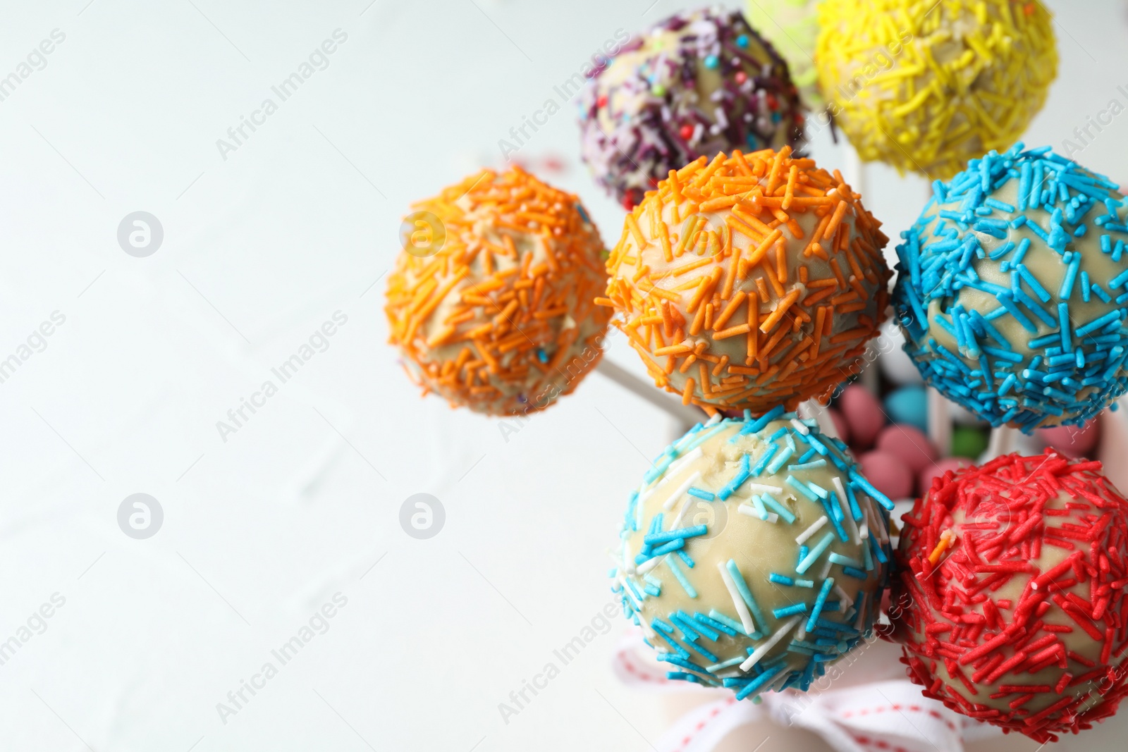 Photo of Yummy colorful cake pops on light background, closeup. Space for text