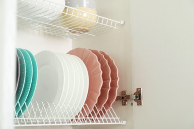 Clean plates and bowls on shelves in cabinet indoors