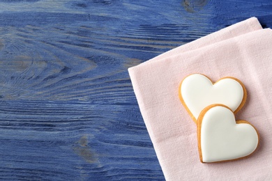 Photo of Decorated heart shaped cookies with napkin and space for text on wooden background, top view