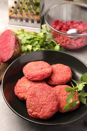 Photo of Delicious beetroot cutlets and parsley in black bowl on table. Vegan dish