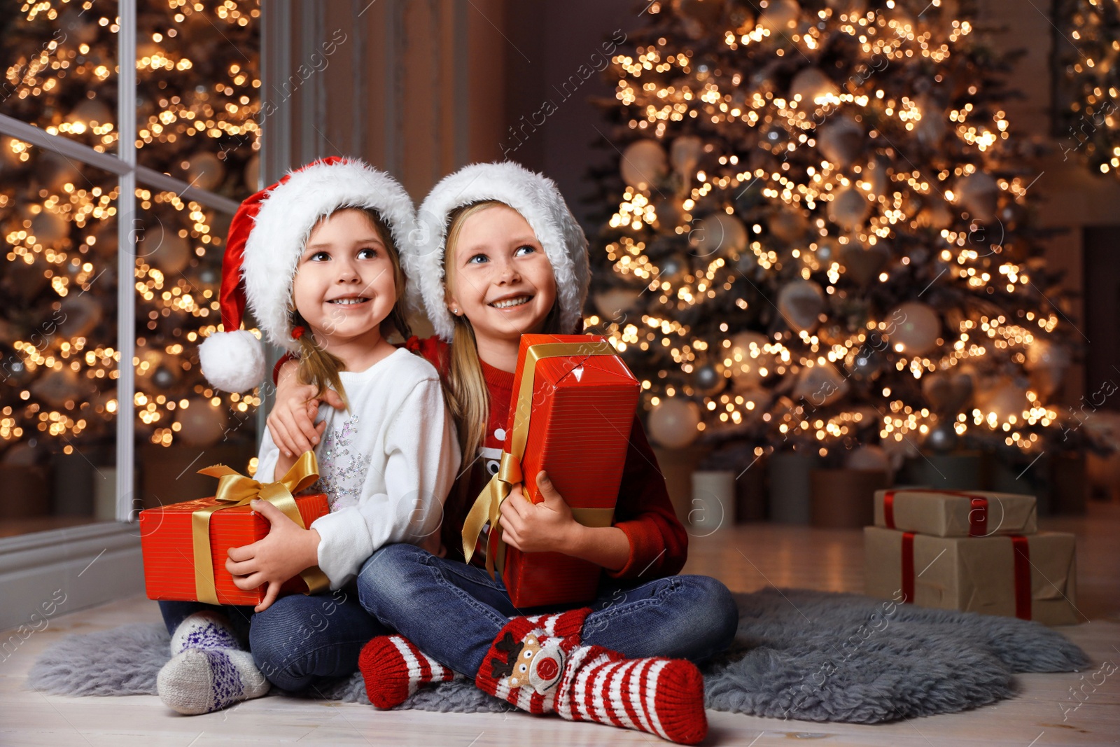 Photo of Cute little children with Christmas gifts at home