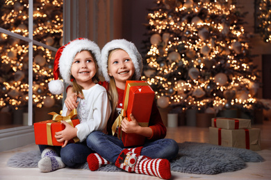 Photo of Cute little children with Christmas gifts at home