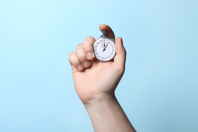 Man holding vintage timer on light blue background, closeup