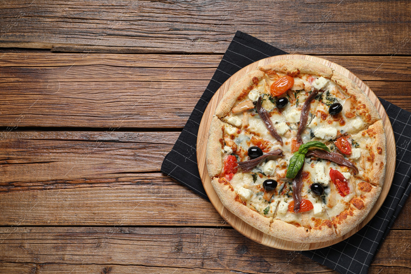 Photo of Tasty pizza with anchovies, basil and olives on wooden table, top view. Space for text