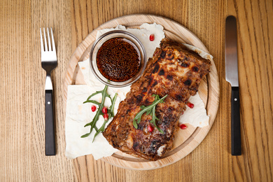 Photo of Delicious grilled ribs served on wooden table, flat lay