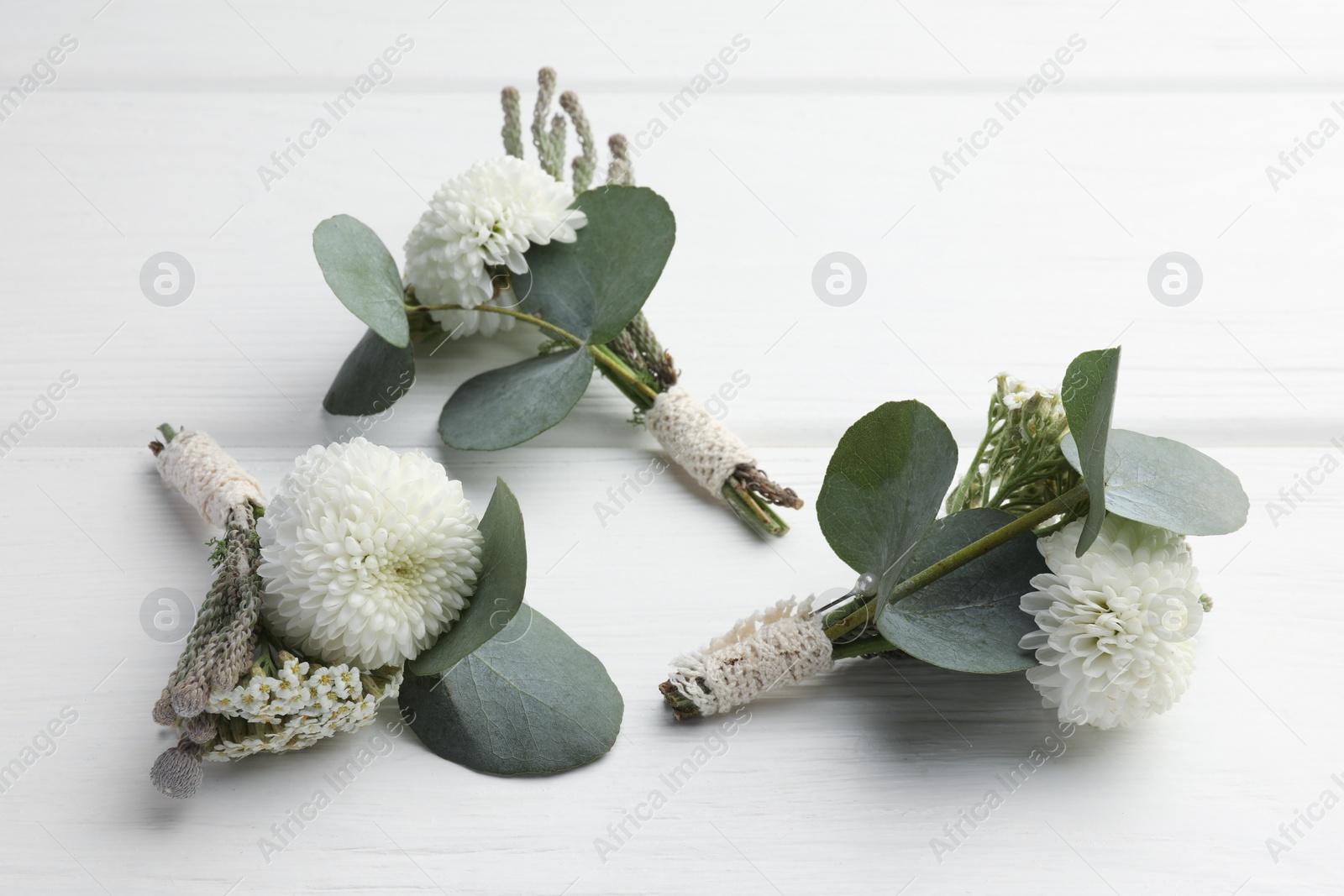 Photo of Small stylish boutonnieres on white wooden table