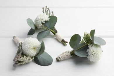 Small stylish boutonnieres on white wooden table