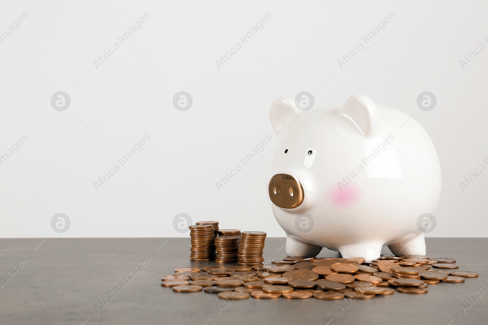 Photo of Piggy bank and coins on table against white background. Space for text