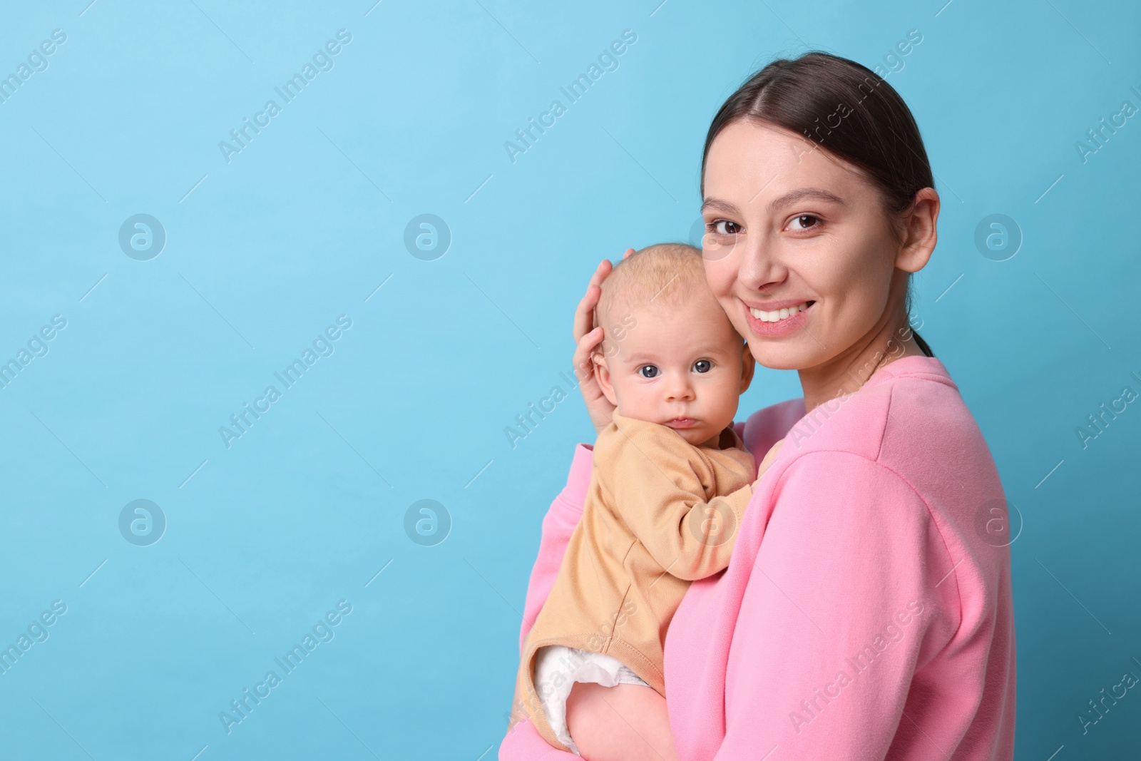 Photo of Happy mother with her cute baby on light blue background, space for text