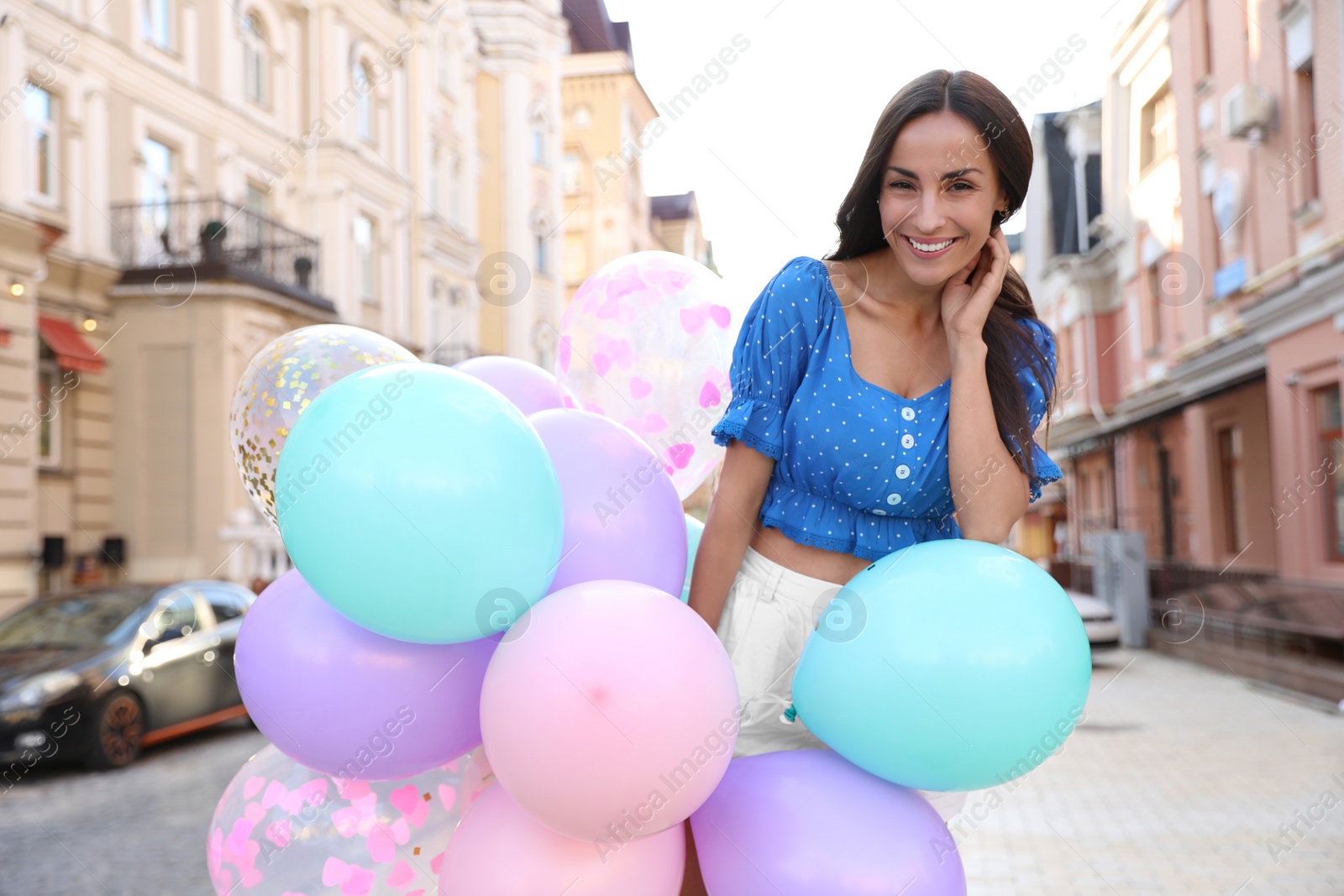 Photo of Beautiful young woman with color balloons on city street