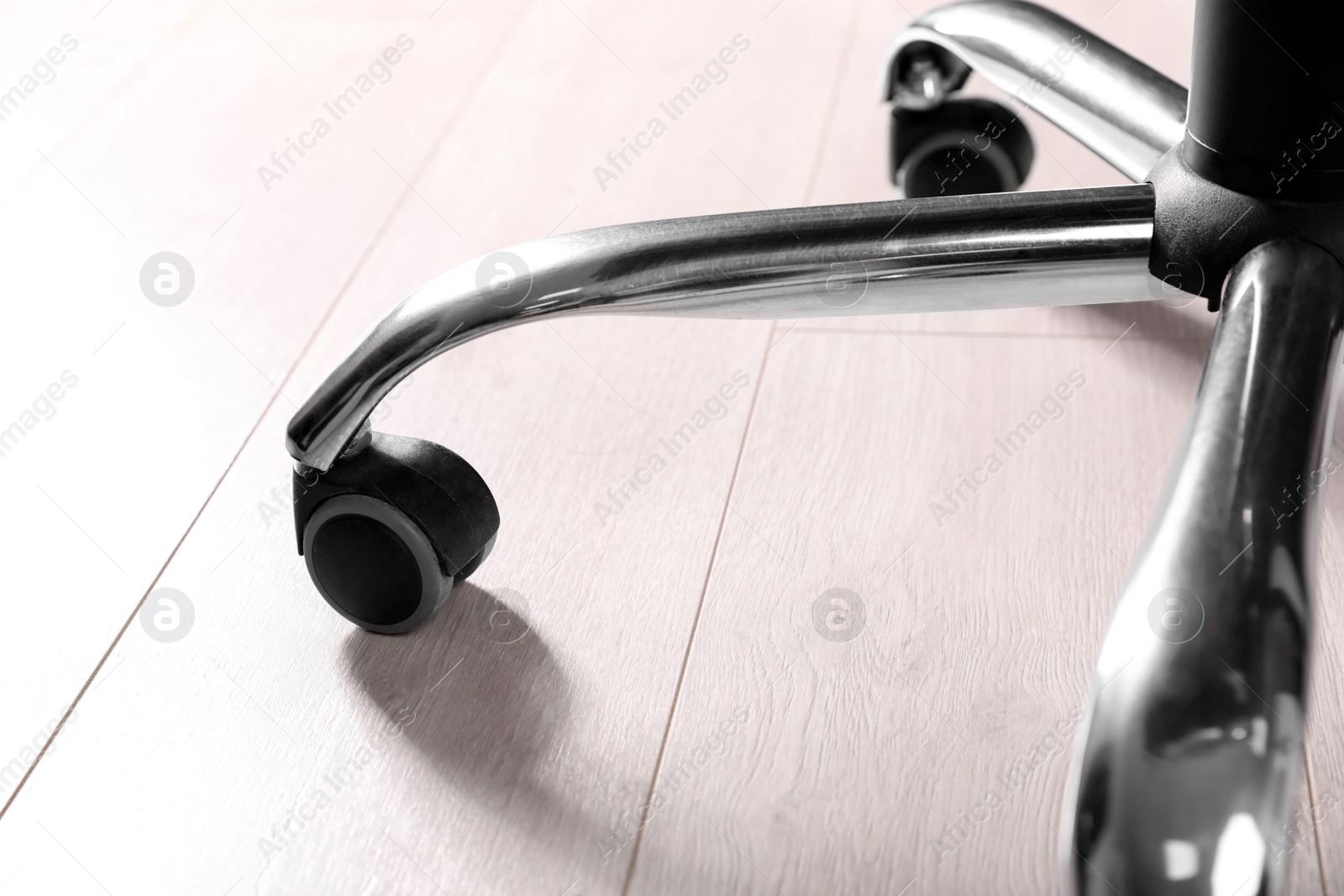 Photo of Modern office chair on wooden floor, closeup. Base with casters