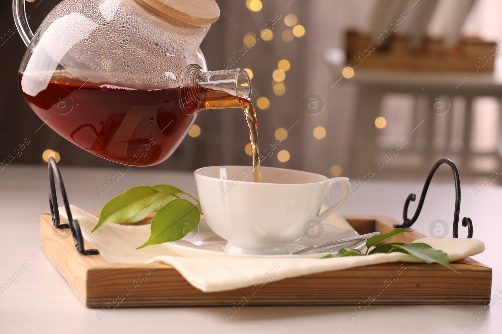 Photo of Pouring tea into cup at light table, closeup