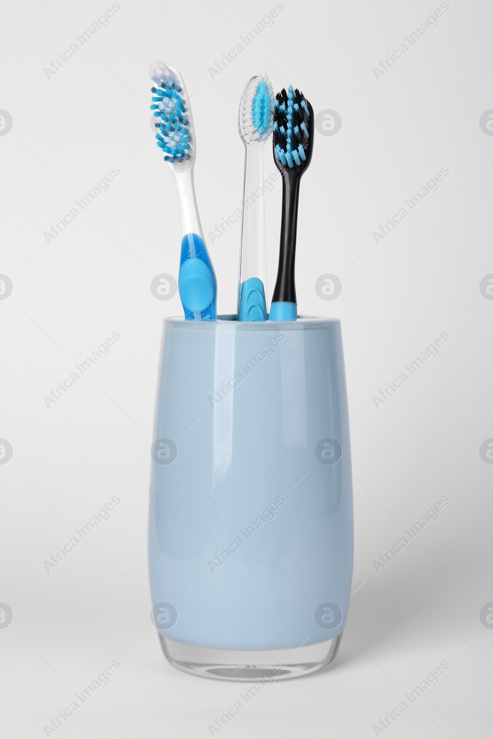 Photo of Different toothbrushes in holder on light grey background