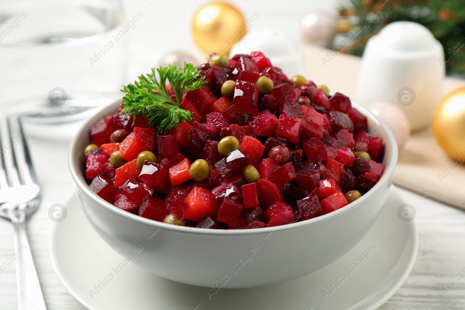 Photo of Traditional Russian salad vinaigrette served on white wooden table, closeup