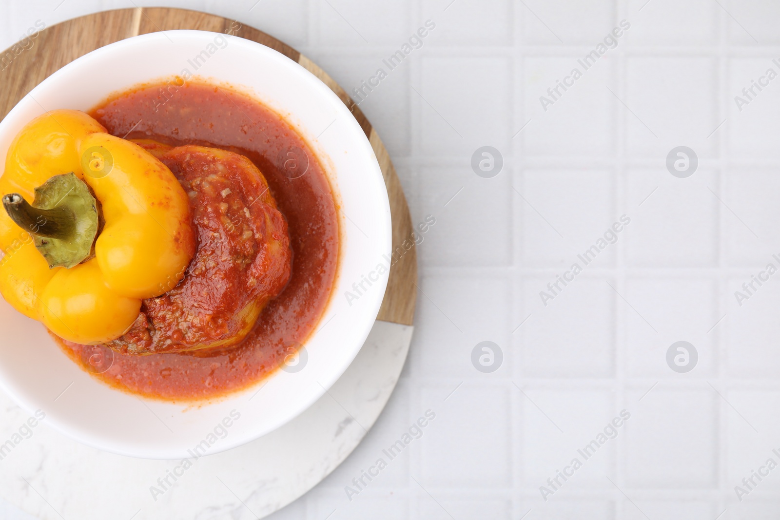 Photo of Delicious stuffed bell pepper on white tiled table, top view. Space for text