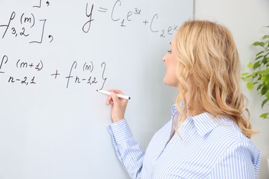 Professor writing down math equation on whiteboard