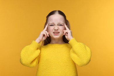 Little girl suffering from headache on yellow background