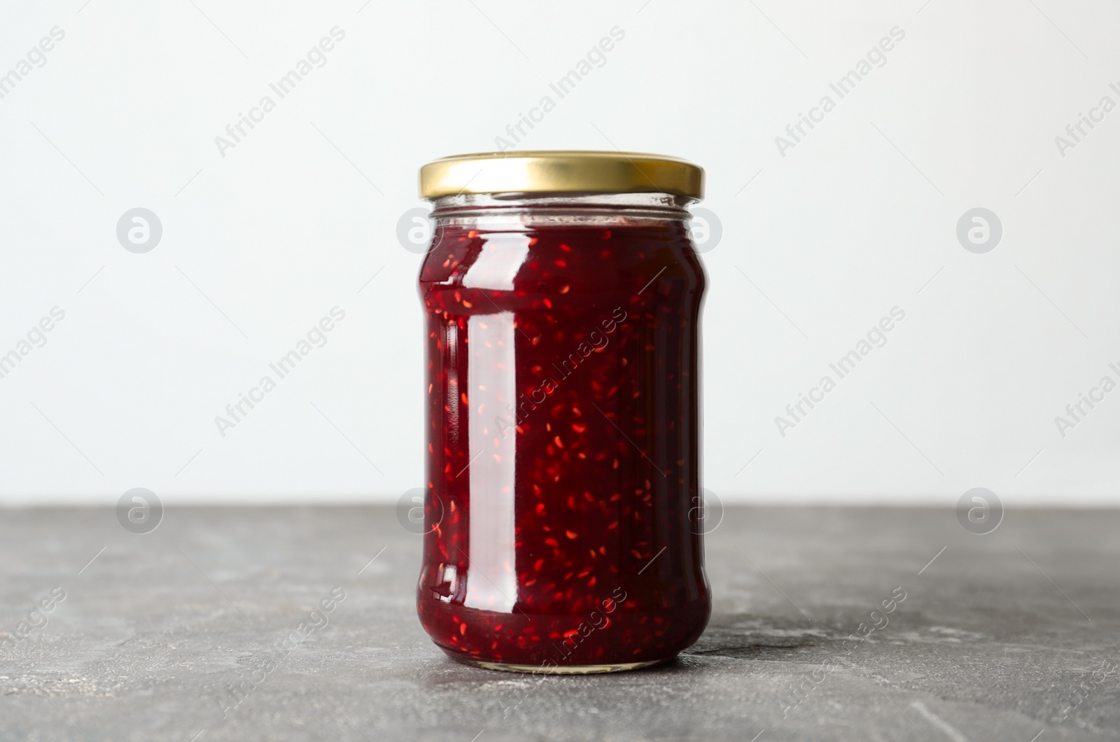 Photo of Jar of raspberry jam on grey table