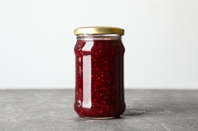 Photo of Jar of raspberry jam on grey table
