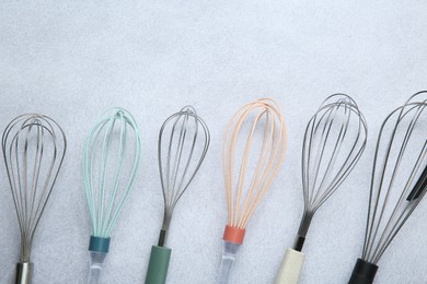 Photo of Different whisks on gray table, flat lay. Space for text