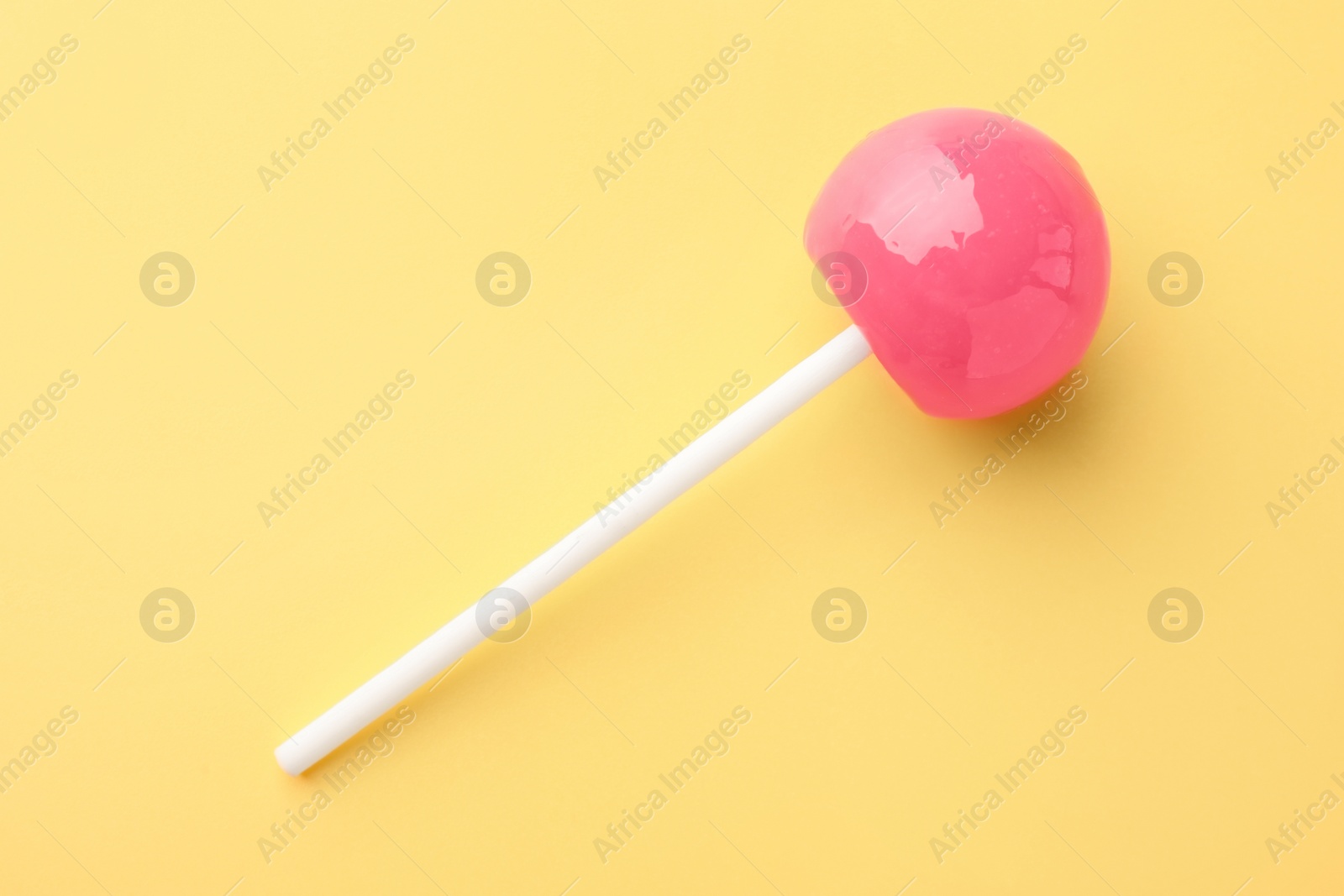 Photo of Tasty lollipop on yellow background, top view