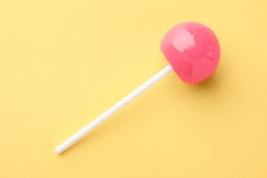 Photo of Tasty lollipop on yellow background, top view