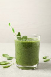 Photo of Green juice and fresh spinach leaves on light grey table