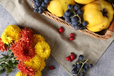 Photo of Flat lay composition with beautiful chrysanthemum flowers, rose hip berries and sweet fruits on grey table