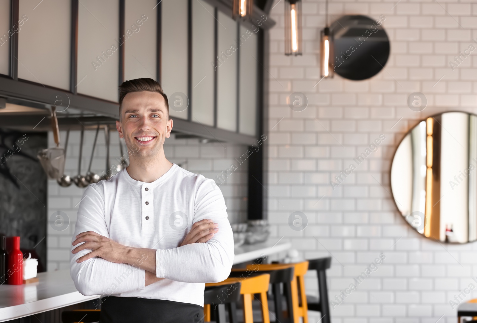 Photo of Portrait of young waiter in uniform at cafe