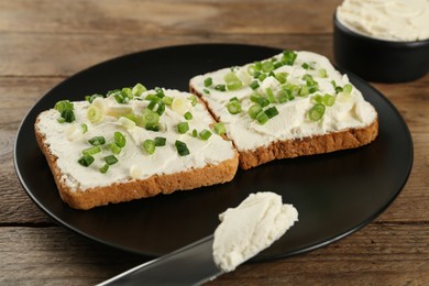 Delicious sandwiches with cream cheese and chives on wooden table