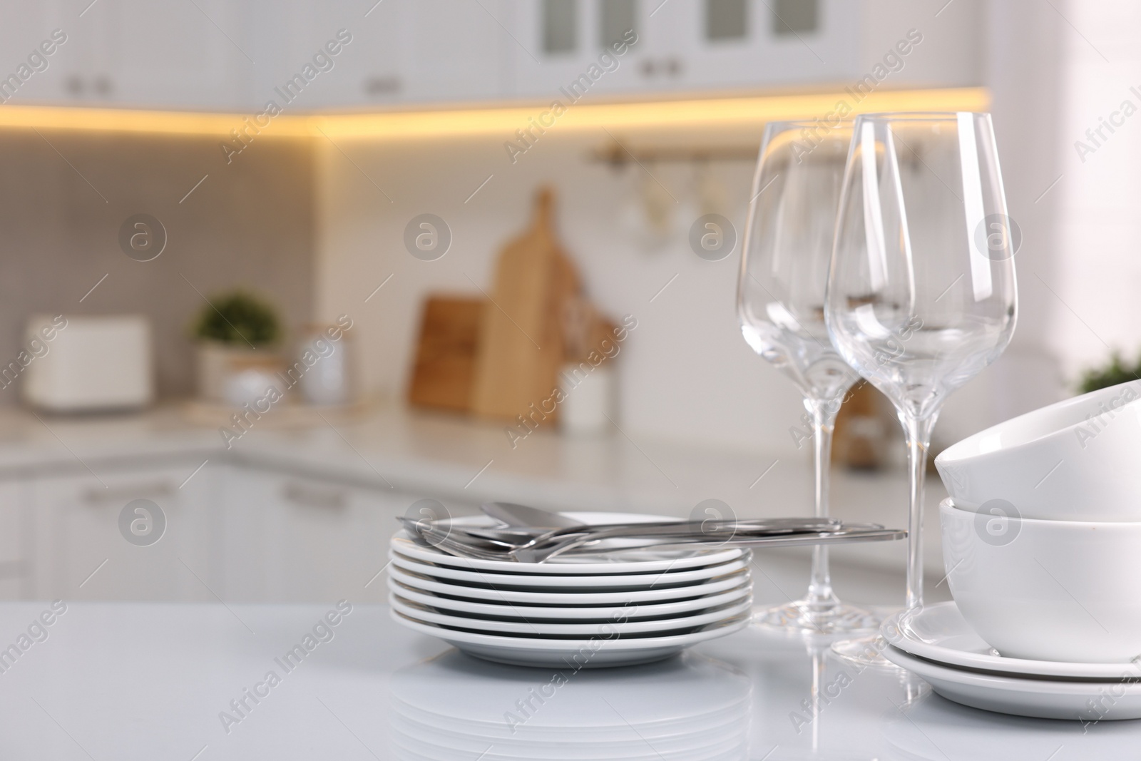 Photo of Set of clean dishware, glasses and cutlery on table in kitchen, space for text