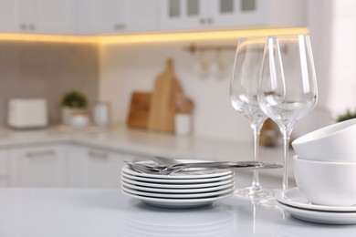 Set of clean dishware, glasses and cutlery on table in kitchen, space for text