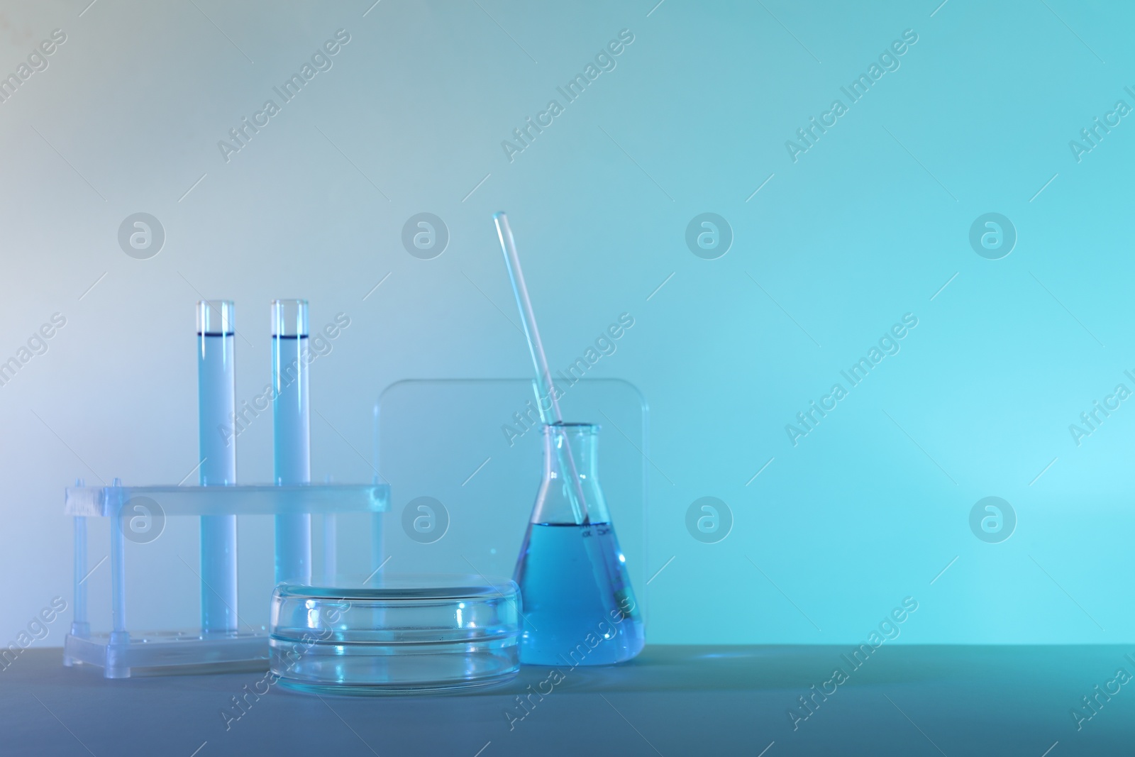 Photo of Laboratory analysis. Different glassware on table against color background, space for text