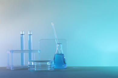 Photo of Laboratory analysis. Different glassware on table against color background, space for text