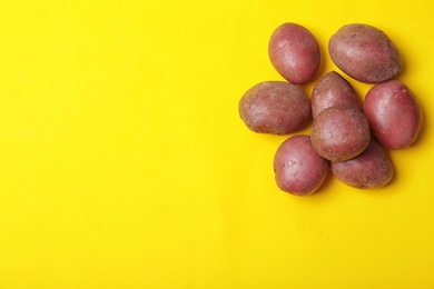 Pile of fresh organic potatoes and space for text on color background, top view