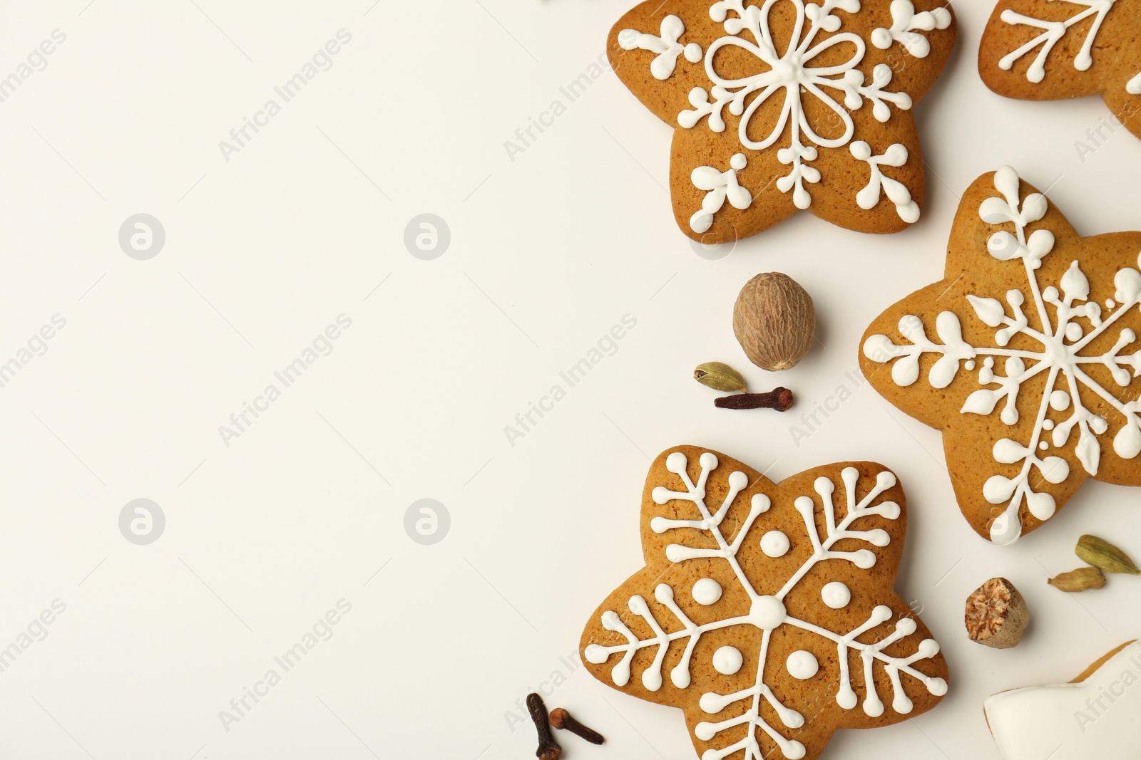 Photo of Tasty Christmas cookies with icing and spices on white background, flat lay. Space for text