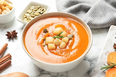 Photo of Bowl of tasty sweet potato soup served on table