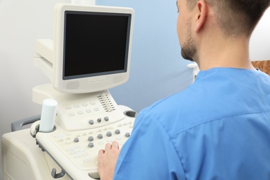 Sonographer operating modern ultrasound machine in clinic