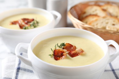 Photo of Tasty potato soup with bacon and rosemary in bowls on white table, closeup