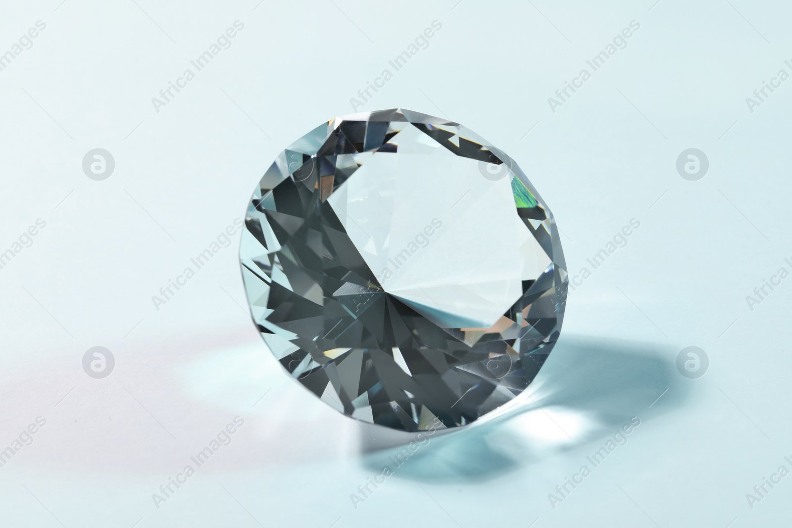 Photo of Beautiful dazzling diamond on turquoise background, closeup