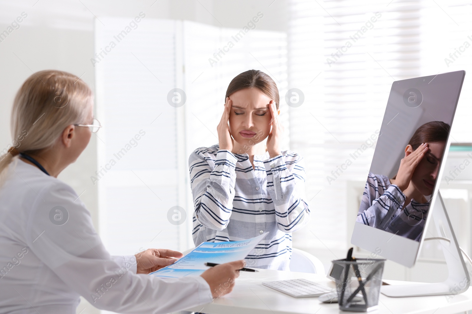 Photo of Doctor consulting patient at desk in clinic