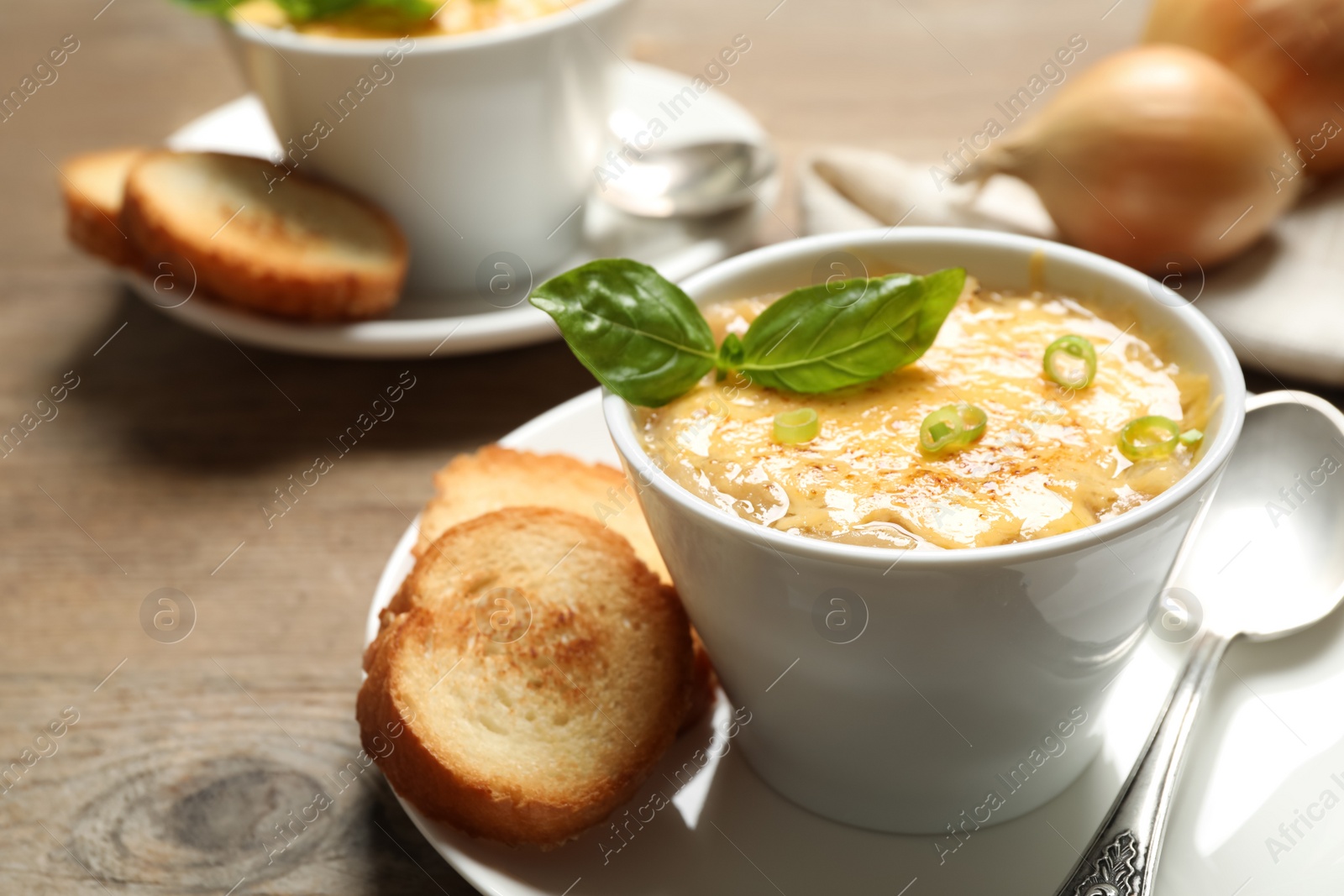 Photo of Tasty homemade french onion soup served on wooden table. Space for text