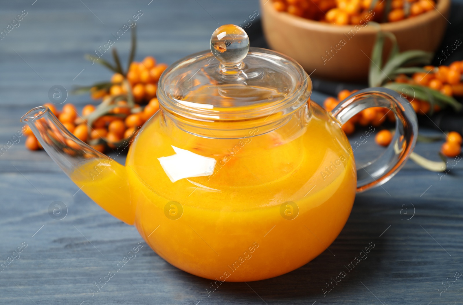 Photo of Delicious sea buckthorn tea and fresh berries on blue wooden table