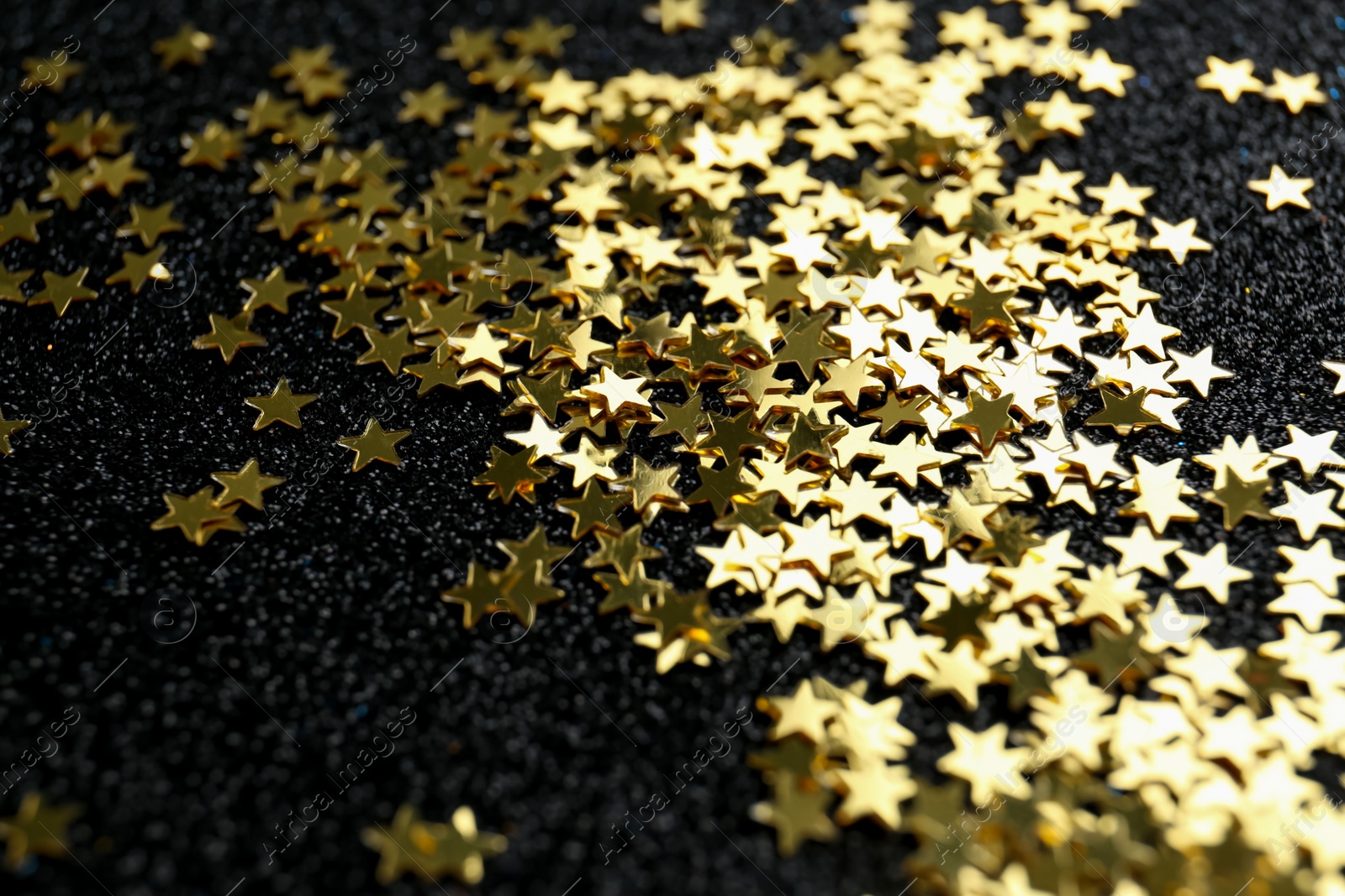 Photo of Confetti stars on black background, closeup. Christmas celebration