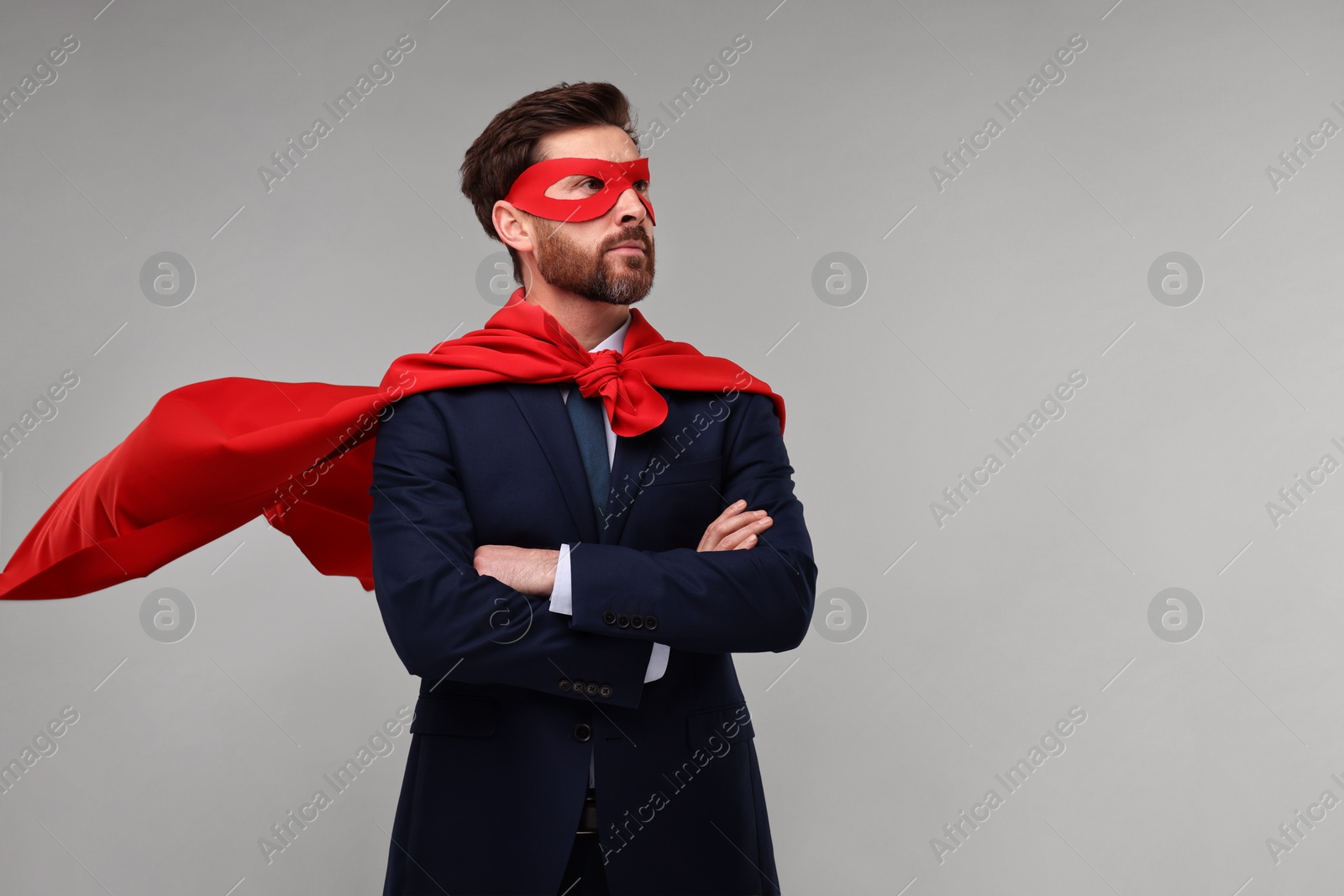 Photo of Confident businessman wearing red superhero cape and mask on beige background. Space for text