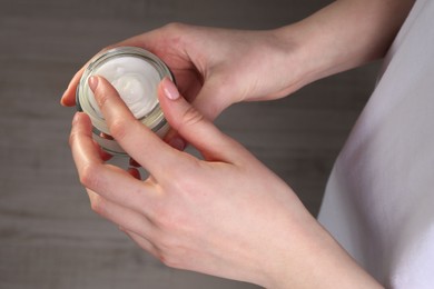 Woman applying hand cream indoors, above view