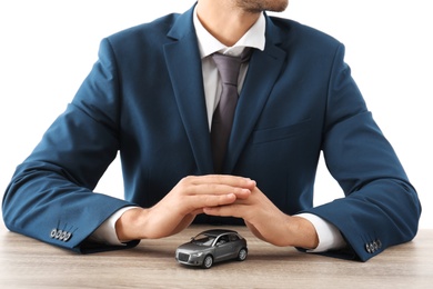 Insurance agent covering toy car on table against white background