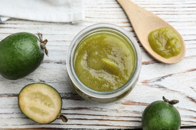 Photo of Feijoa jam and fresh fruits on white wooden table, flat lay