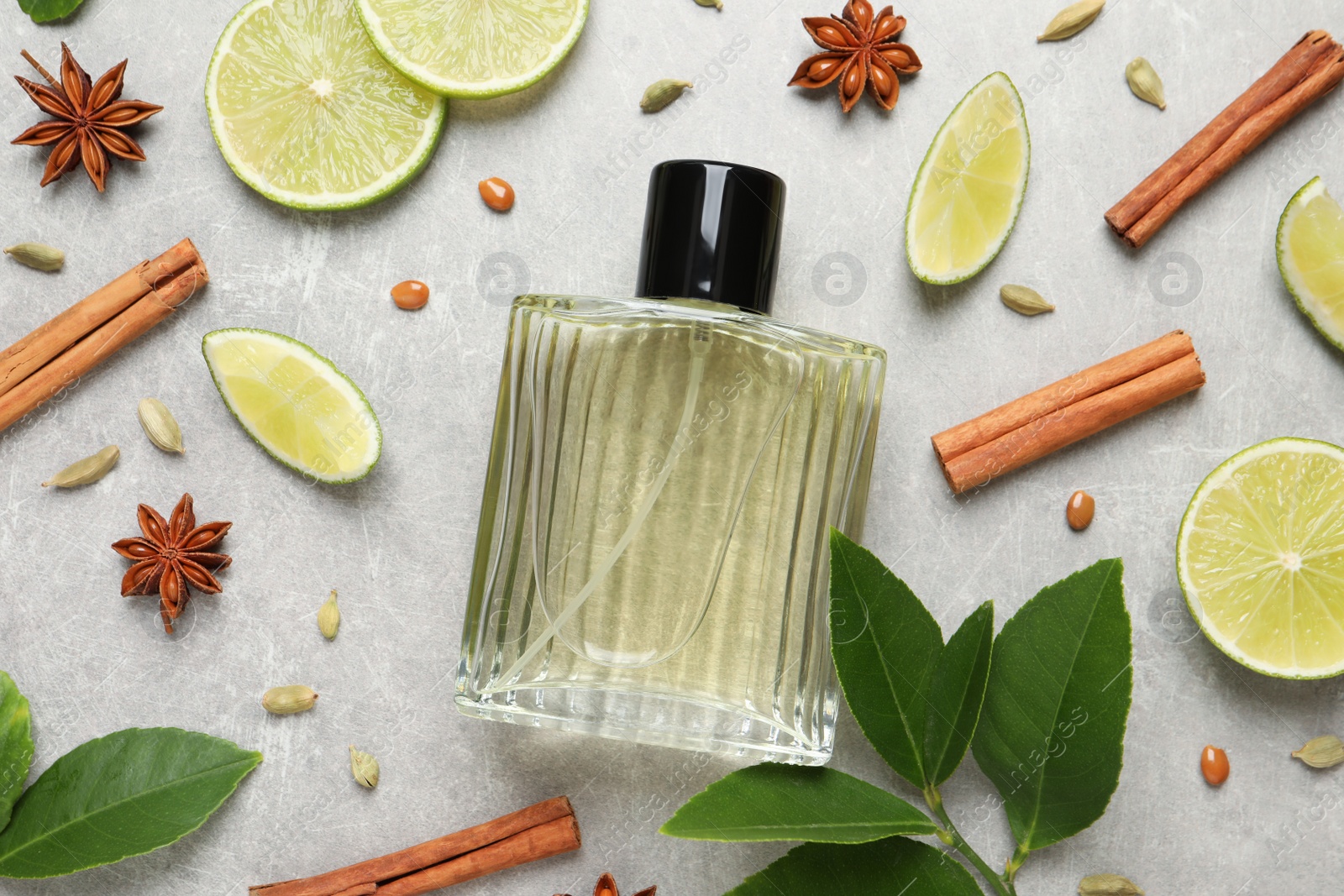 Photo of Flat lay composition with bottle of perfume, lime and spices on light grey background