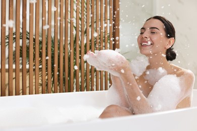 Beautiful young woman taking bubble bath at home